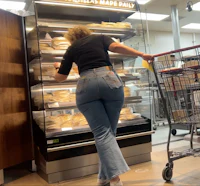a woman shopping in a grocery store with a cart full of food