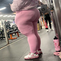 a woman is standing in a gym wearing pink leggings