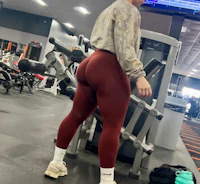 a woman standing in a gym in burgundy leggings