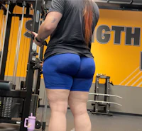 a woman in blue shorts lifting weights in a gym