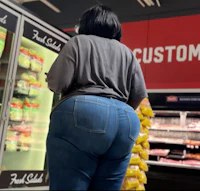 a woman is standing in front of a refrigerator in a grocery store