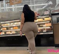 a woman is standing in front of a bakery case